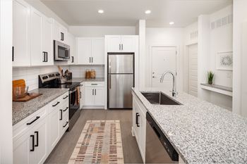 A modern kitchen with white cabinets and a granite countertop.